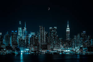 新月下，璀璨燈光倒映在水中的城市天際線夜景。