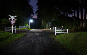 夜間由單一路燈照亮的鐵路平交道碎石路。