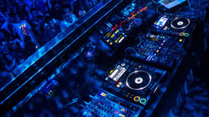 DJ booth with glowing controls and a crowd in a nightclub under blue lights. — 音樂美學 壁紙