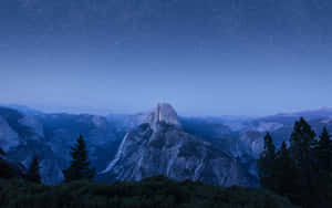 半圓頂山在繁星點點的夜空下，前景有松樹