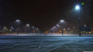 白雪覆蓋的空停車場，夜晚被街燈照亮
