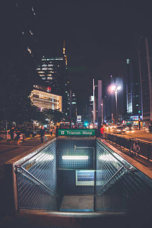 繁華城市中的夜晚地鐵入口，有明亮的摩天大樓和街燈。 — 夜景城市 壁紙