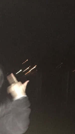 手握住發光物體，在黑暗的夜晚中創造光線條紋。 — 夜晚 GIF 壁紙