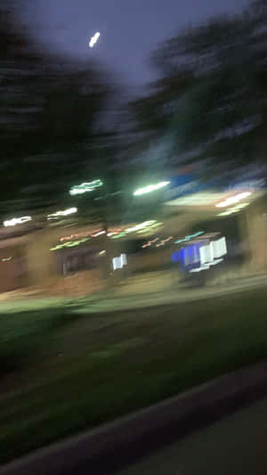 從行駛中的車輛看到的夜間街景，帶有模糊的燈光和樹木。 — 夜晚 GIF 壁紙