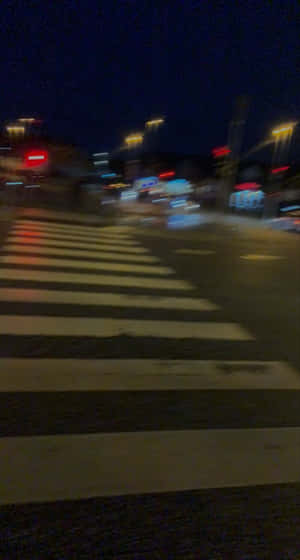 夜晚街道，模糊車燈與街燈下的行人過路處。