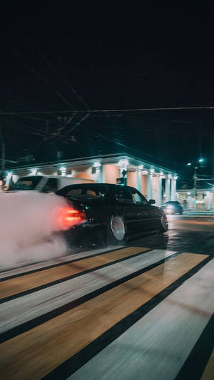 夜間飄移的黑色汽車，背景有煙霧和霓虹燈。