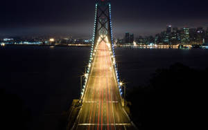 夜晚亮燈的吊橋，帶有流動的交通燈光和發光的城市天際線。