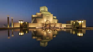 現代博物館建築，幾何設計，在暮色中平靜的水池中倒映。 — 藍天 壁紙