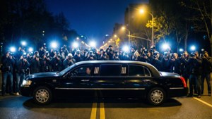 黑色豪華轎車在夜間被攝影師的閃光燈包圍。