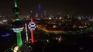 兩座發光的塔樓在夜間城市景觀上閃爍著鮮豔的色彩。 — 夜晚 GIF 壁紙