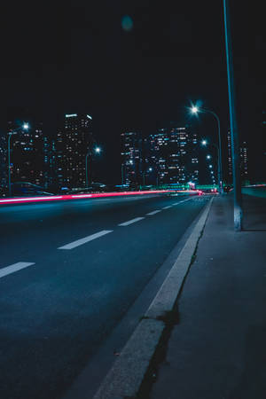 夜間城市街道，有移動車輛的紅色光軌和照明建築。