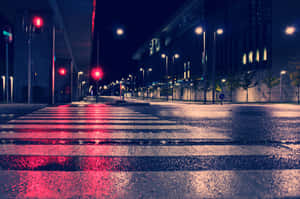 夜雨中的城市街道，濕漉漉的路面反射出紅色斑馬線燈光。 — 夜景城市 壁紙