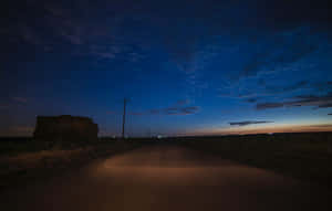 在繁星點點的夜空下，一條黑暗的道路，遠處有城市燈光。