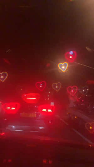 心形燈光在夜空中發光，映照在道路上汽車的煞車燈上方。 — 汽車 壁紙