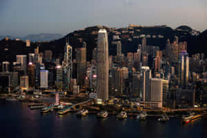黃昏時分的香港城市景觀，閃爍的摩天大樓和港灣船隻。 — MacBook Air M4 壁紙