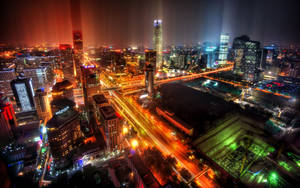 繁華城市的空中夜景，發光的建築物和流動的汽車燈光。 — 城市 壁紙