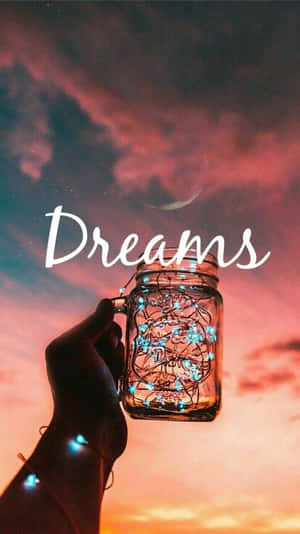 手拿著發光燈的瓶子，背景是帶有新月和Dreams字樣的暮色天空。