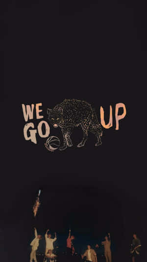 狼手持籃球，上方有「We Go Up」字樣，下方是現場樂隊在舞台上。