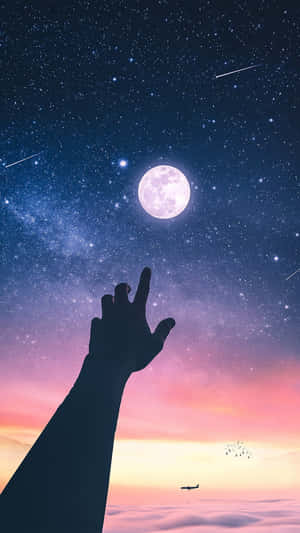 在暮色中，一隻手伸向雲層之上的月亮和星星。
