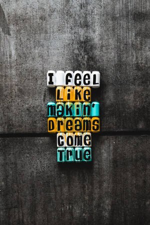 混凝土牆上寫住 'I feel like makin' dreams come true' 嘅勵志文字方塊。