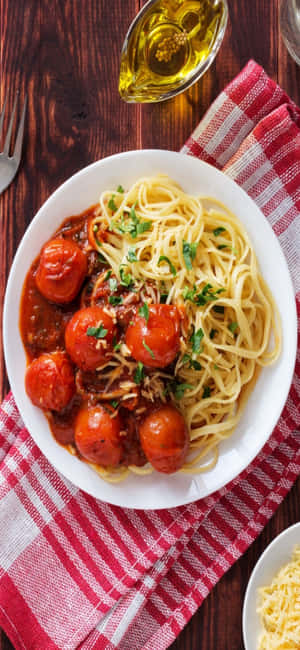 意大利麵配番茄醬和烤櫻桃番茄，放在格紋布上。 — iPhone 18 壁紙