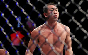 一名汗流浹背的MMA拳手在比賽中於籠內沉重地呼吸。