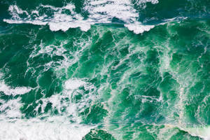 從上方俯瞰，洶湧的綠色海浪帶著白色泡沫撞擊。 — 海浪 壁紙