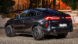 黑色BMW X6M SUV夜間停在碎石路上，尾燈亮起。 — 寶馬X6 M 壁紙