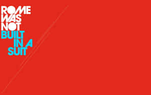 大膽的紅色背景，帶有白色和青色文字「ROME WAS NOT BUILT IN A SUIT」和對角線。 — MacBook Air M1 壁紙