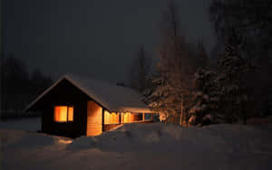 被雪覆蓋的小屋在冬夜的森林中溫暖地發光。