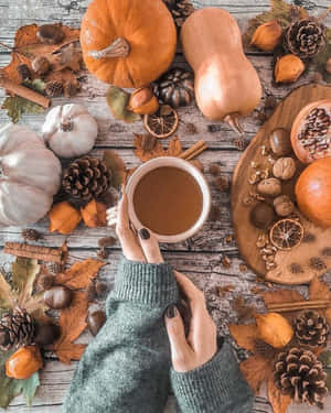 Hands holding a mug of coffee surrounded by autumn decorations on a wooden table. — 秋天 壁紙