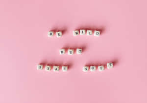 在粉紅色背景上拼出「Be Wild But Stay Soft」的白色字母方塊。