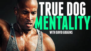 一個肌肉發達、表情堅定的男人穿著破爛背心，上面有文字true dog mentality with david goggins。