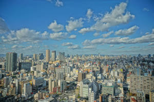 在晴朗藍天白雲下，高樓林立的密集城市全景。 — 東京 壁紙