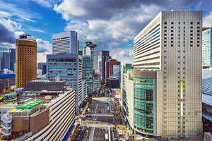 密集城市區域的鳥瞰圖，高樓大廈和繁忙的街道，在部分多雲的天空下。 — 東京 壁紙