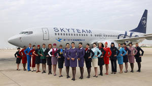 一群穿著色彩繽紛制服的航空公司員工在飛機前擺姿勢。