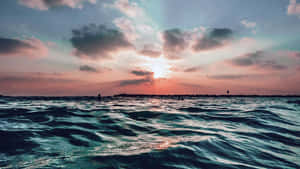 海洋上的夕陽，有雲和遠處陸地