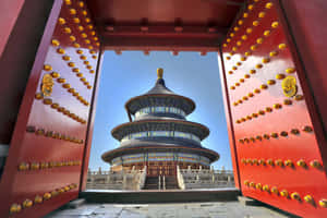 紅色大門框著一座層疊的寺廟，背景是清澈的藍天。 — 中國 壁紙
