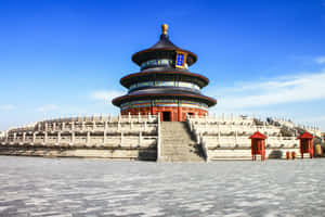圓形中國寺廟，藍色屋頂和紅色柱子，在明亮的藍天下。