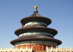 宏偉的分層寺廟，藍色屋頂和金色尖頂，在清澈的藍天下。 — 中文 壁紙
