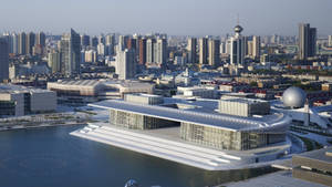 日落時分，城市天際線中水邊的現代白色建築群，帶有玻璃牆。 — 唐人街 GIF 壁紙