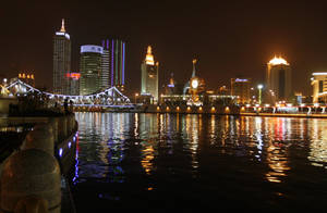 城市天際線的夜景，有明亮的建築物和水上的橋樑。 — 唐人街 GIF 壁紙