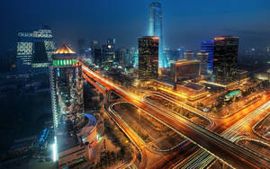 夜晚的城市景觀，摩天大樓燈火通明，車流光軌閃爍。 — 唐人街 GIF 壁紙