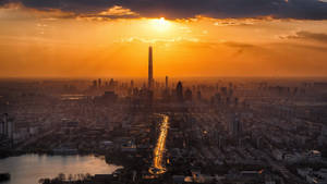 夕陽落在密集的城市天際線上，金色光芒照亮摩天大樓和主要高速公路。