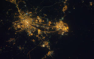 從高空俯瞰夜晚的城市，金色燈光在黑暗的天空下閃耀。
