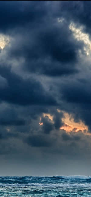 帶有烏雲和橙色夕陽穿透的暴風雨海洋。