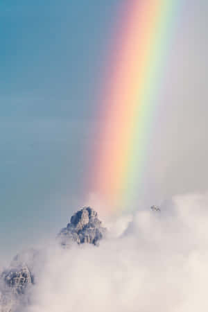 彩虹從天空降落到雲層之上的山峰。