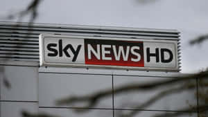建築物上的 Sky News HD 標誌，前面有樹枝。