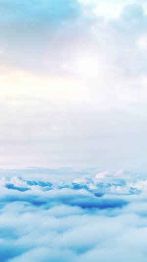 在柔和的藍白天空中，雲層之上有溫和的太陽耀斑。