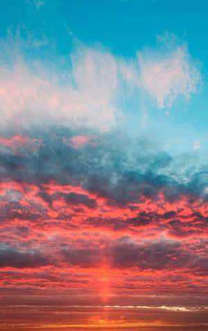 平靜地平線上空日落時分鮮豔的紅色和藍色雲彩。